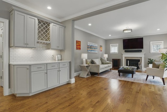 living area featuring light wood-type flooring, recessed lighting, a fireplace, and ornamental molding