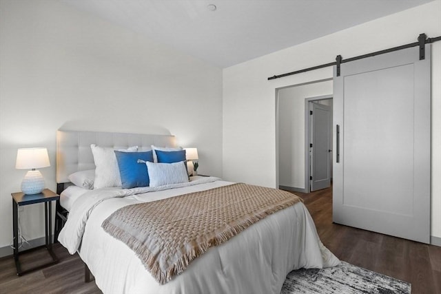 bedroom with dark hardwood / wood-style floors and a barn door