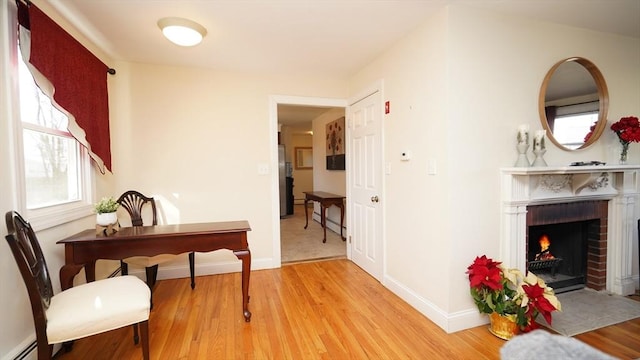 interior space with a fireplace, a baseboard radiator, and light hardwood / wood-style flooring