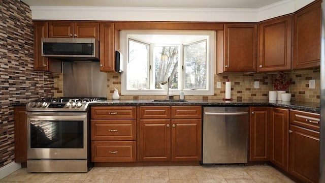 kitchen featuring backsplash, dark stone counters, sink, ornamental molding, and appliances with stainless steel finishes