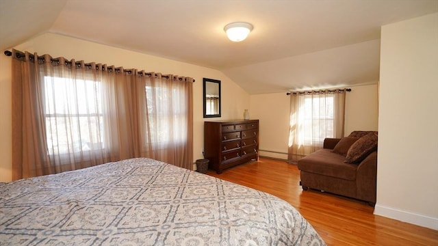 bedroom featuring hardwood / wood-style floors, lofted ceiling, and a baseboard heating unit