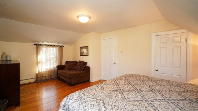 bedroom featuring baseboard heating, lofted ceiling, and hardwood / wood-style flooring