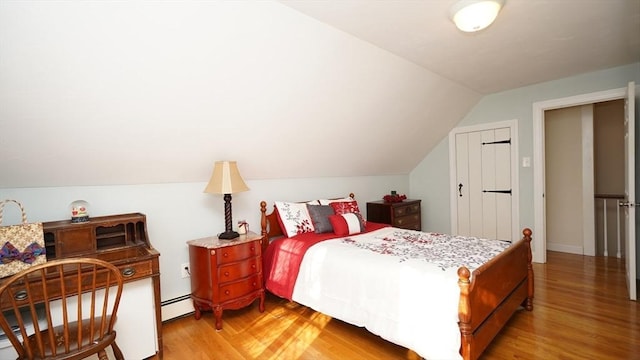 bedroom featuring hardwood / wood-style floors, a baseboard radiator, and vaulted ceiling