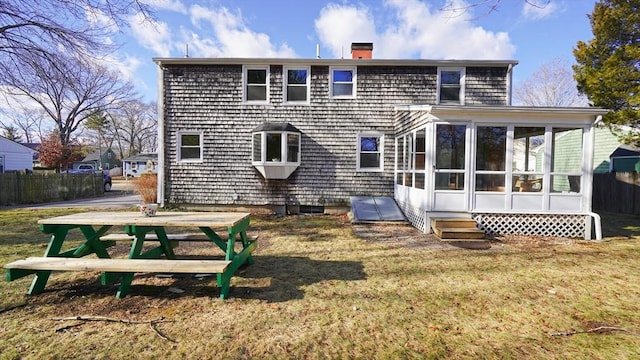 rear view of house with a sunroom and a lawn