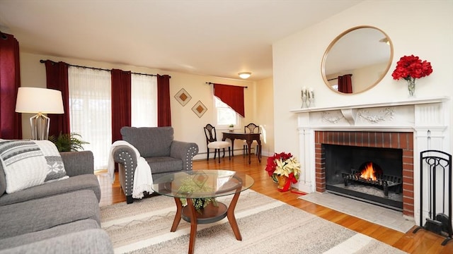 living room with light hardwood / wood-style floors, a brick fireplace, and a baseboard radiator