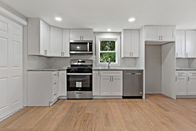 kitchen featuring stainless steel appliances, white cabinetry, and light hardwood / wood-style flooring