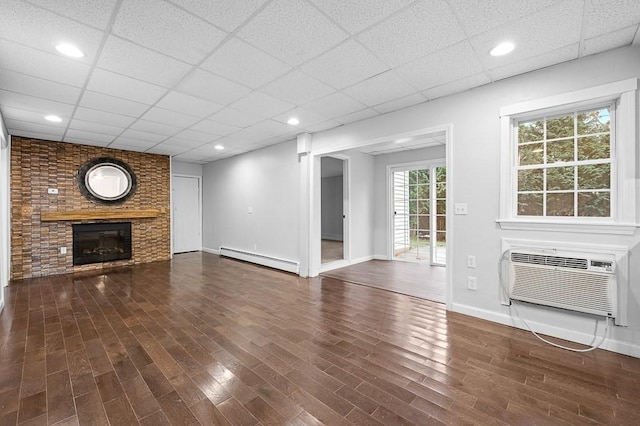 853 Oxford St S, Auburn, MA 01501 - unfurnished living room with a baseboard heating unit, a wall mounted AC, wood finished floors, a paneled ceiling, and a fireplace