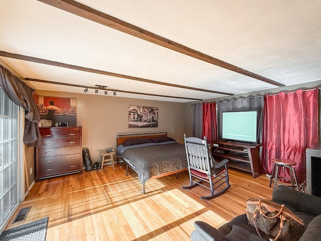 bedroom with beam ceiling and hardwood / wood-style floors