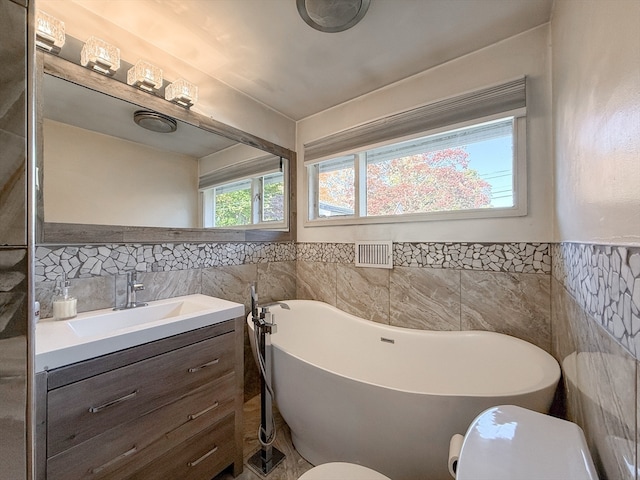 bathroom featuring vanity, toilet, tile walls, and a tub