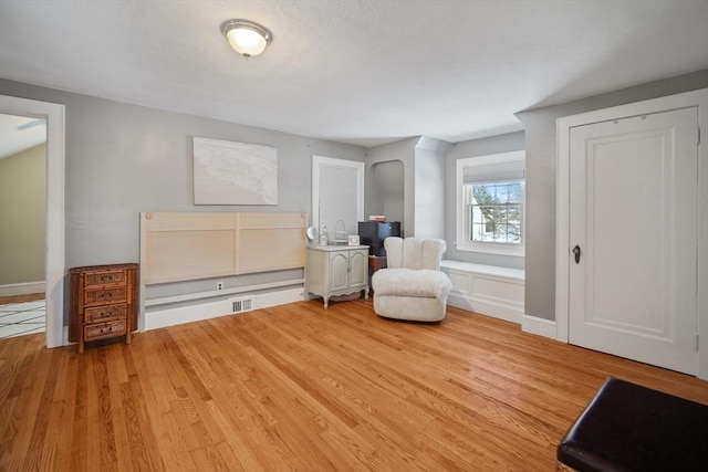 sitting room featuring light wood-style floors, visible vents, and baseboards