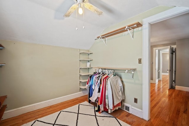 spacious closet featuring lofted ceiling, visible vents, ceiling fan, and wood finished floors