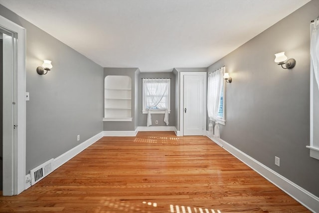 unfurnished room featuring visible vents, light wood-style flooring, and baseboards