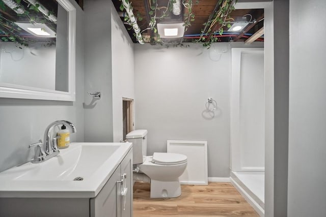 full bathroom with toilet, baseboards, wood finished floors, and vanity