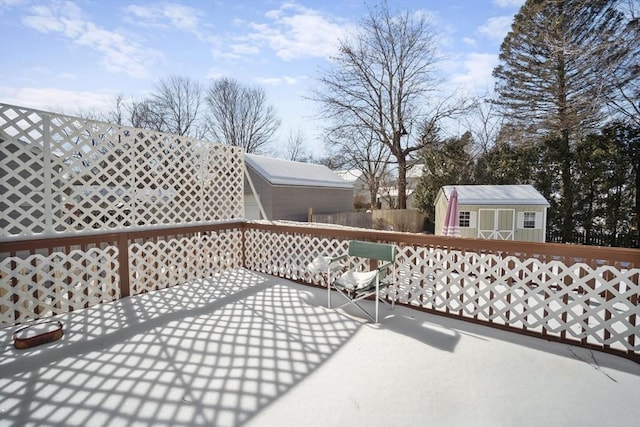 wooden deck featuring an outdoor structure, fence, and a storage unit