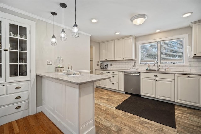 kitchen featuring a peninsula, a sink, white cabinets, stainless steel dishwasher, and glass insert cabinets