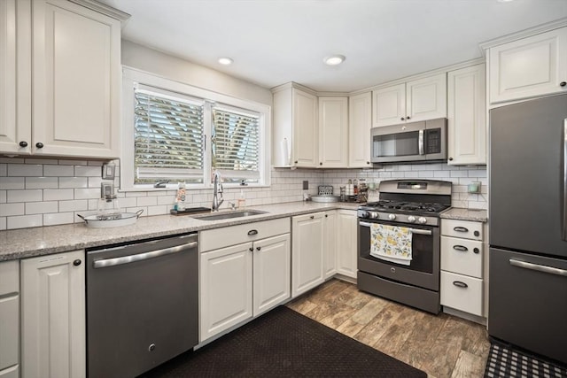 kitchen featuring stainless steel appliances, a sink, white cabinetry, dark wood-style floors, and tasteful backsplash