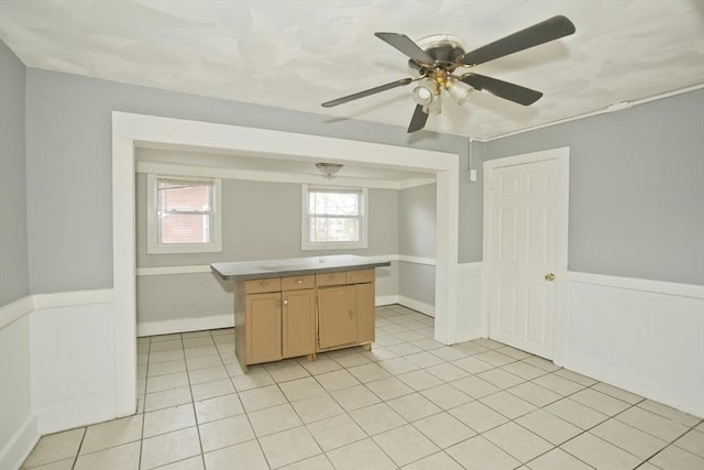 74 Everett St, Springfield, MA 01104 - kitchen with a center island, a ceiling fan, a wainscoted wall, and light tile patterned flooring