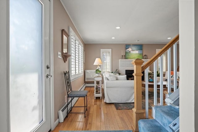 12 14th St, Newbury, MA 01951 - living room with a baseboard radiator, light wood finished floors, a fireplace, stairs, and recessed lighting