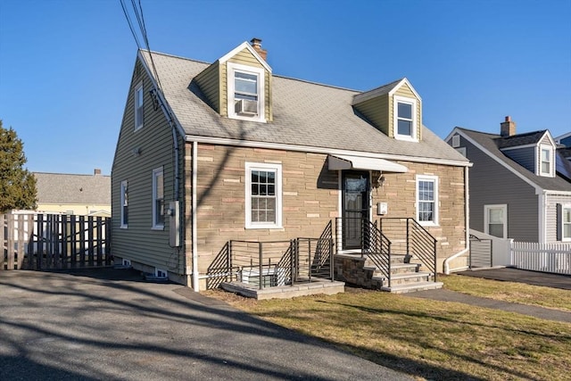 new england style home with stone siding, cooling unit, a front lawn, and fence