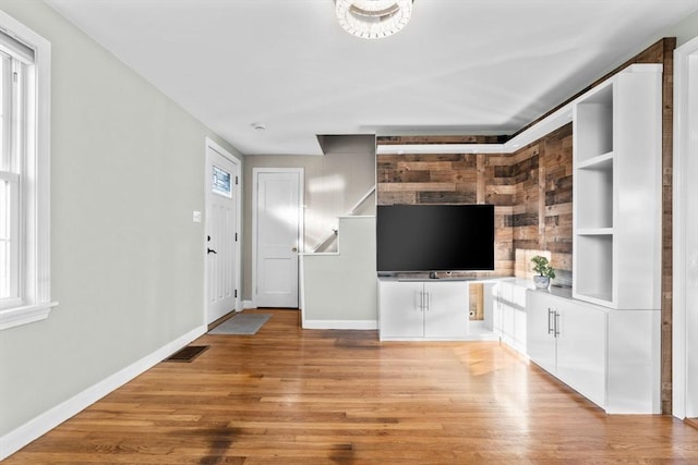 unfurnished living room with plenty of natural light, light wood-style floors, visible vents, and baseboards