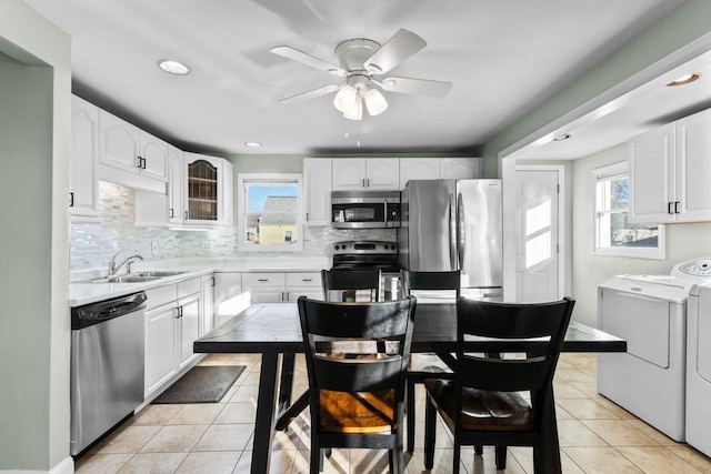 kitchen with a sink, backsplash, stainless steel appliances, separate washer and dryer, and light tile patterned flooring