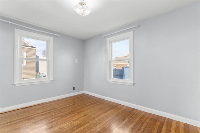 spare room with light wood-type flooring, baseboards, and a healthy amount of sunlight