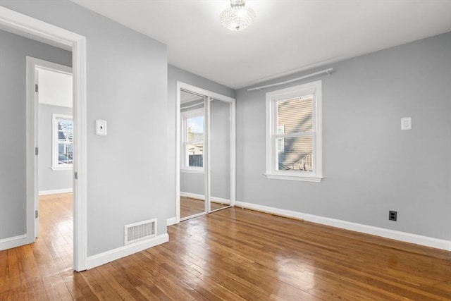 unfurnished bedroom featuring a closet, visible vents, baseboards, and hardwood / wood-style floors