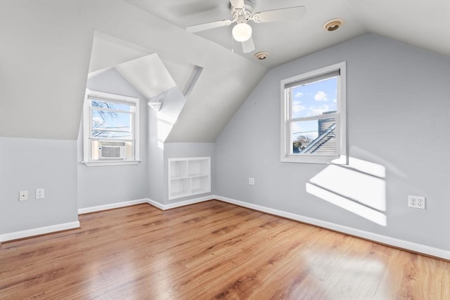 additional living space featuring built in shelves, lofted ceiling, wood finished floors, baseboards, and ceiling fan