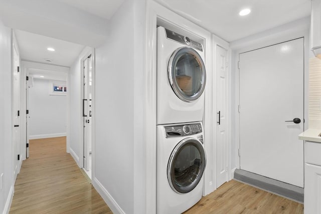 washroom featuring stacked washer and dryer, recessed lighting, light wood-style floors, baseboards, and laundry area