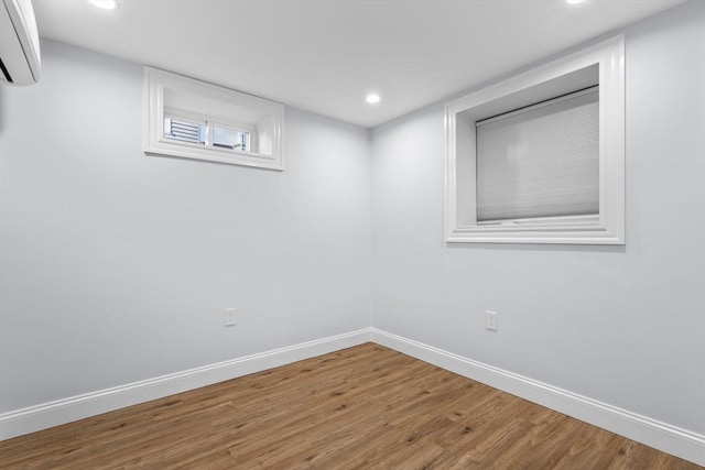 unfurnished room featuring recessed lighting, baseboards, an AC wall unit, and wood finished floors