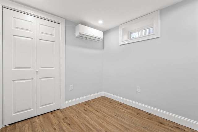 interior space featuring baseboards, light wood finished floors, a wall mounted AC, recessed lighting, and a closet