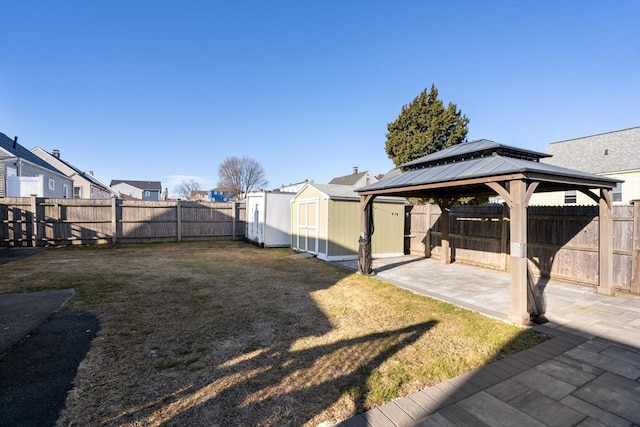 view of yard featuring a gazebo, a storage shed, an outbuilding, and a fenced backyard