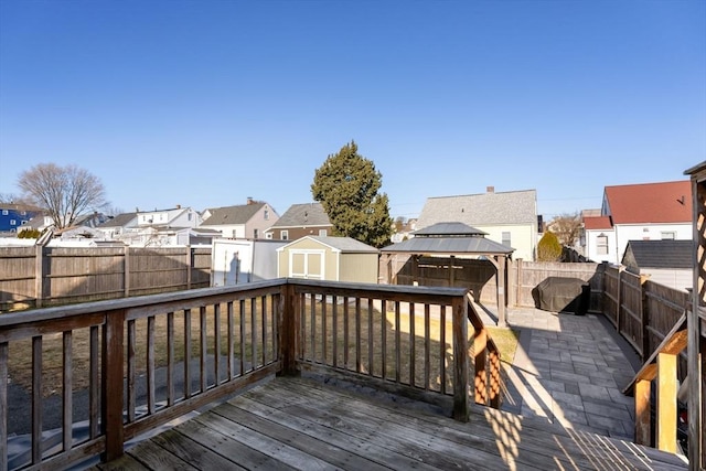 wooden deck with a gazebo, a fenced backyard, a residential view, and a shed