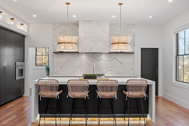 kitchen with stainless steel oven, light countertops, and light wood-type flooring