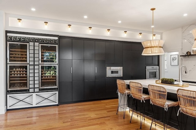 kitchen featuring beverage cooler, dark cabinets, and stainless steel oven