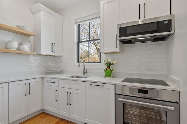 kitchen featuring tasteful backsplash, light countertops, appliances with stainless steel finishes, white cabinets, and a sink