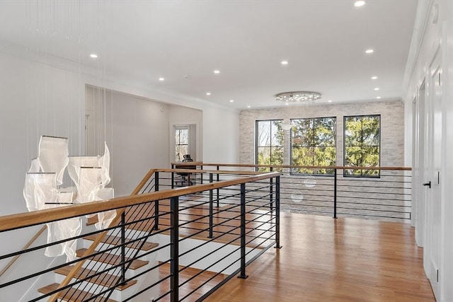 hallway with an upstairs landing, recessed lighting, crown molding, and wood finished floors