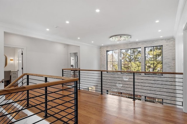 hall with wood finished floors, crown molding, recessed lighting, and an upstairs landing