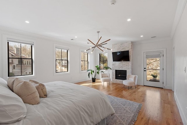 bedroom with baseboards, a large fireplace, light wood-style floors, and crown molding