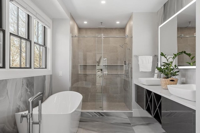 bathroom featuring a sink, a freestanding tub, recessed lighting, and a shower stall