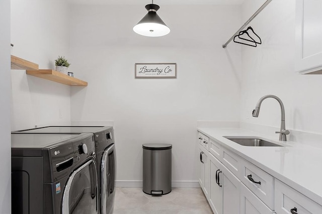 laundry room with cabinet space, separate washer and dryer, baseboards, and a sink