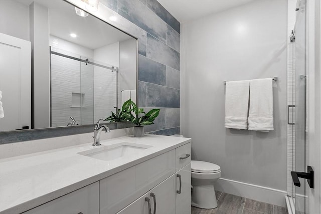 full bathroom featuring vanity, wood finished floors, baseboards, a stall shower, and toilet