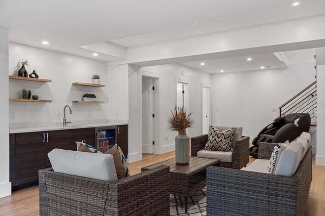 living room with baseboards, recessed lighting, indoor wet bar, wine cooler, and light wood-type flooring