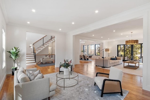 living room featuring light wood-style flooring, stairs, and ornamental molding