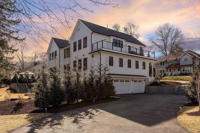 view of front of house with aphalt driveway, an attached garage, and a balcony