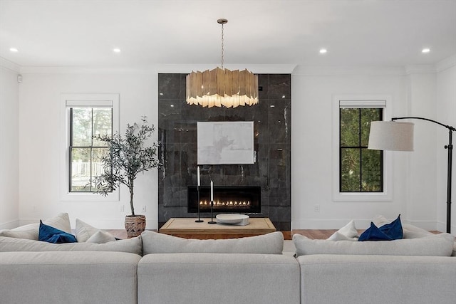 living room with a wealth of natural light, recessed lighting, crown molding, and a premium fireplace