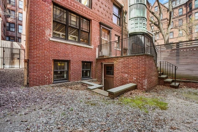 rear view of house featuring brick siding and fence