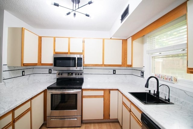 369 Aiken Ave Unit 15, Lowell, MA 01850 - kitchen with stainless steel appliances, a sink, a chandelier, decorative backsplash, and a textured ceiling