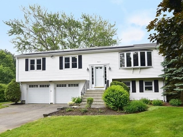 767 S Main St, Bellingham, MA 02019 - raised ranch featuring a front yard, a garage, driveway, and solar panels