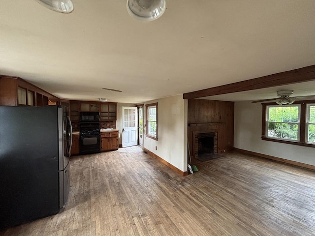 15 Reid Ave, Yarmouth, MA 02673 - kitchen featuring black appliances, a large fireplace, light wood-style flooring, and open floor plan